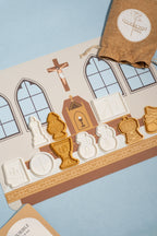 A flat-lay product shot of a Catholic silicone mat, plastic molds and a drawstring bag. The plastic molds are shaped to resemble the pieces of a Catholic Mass. 