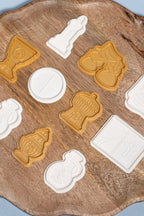 A set of plastic play dough molds of items used during a catholic mass. these items include a candle, bells, chalice, host, ciborium, missal, thurible and wine decanter displayed on a wooden plate. 