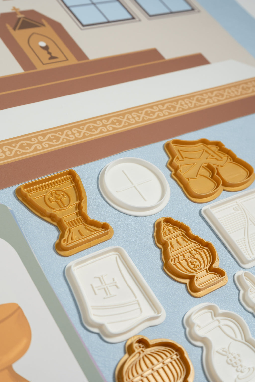 A close-up showing several small plastic play dough molds that depict religious pieces used during a catholic mass.